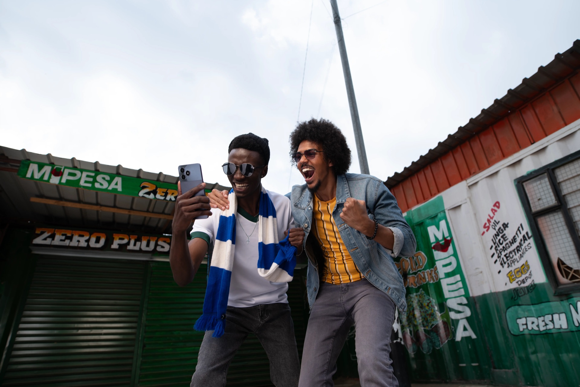 Original photograph of two football fans celebrating at a phone under a flat grey sky