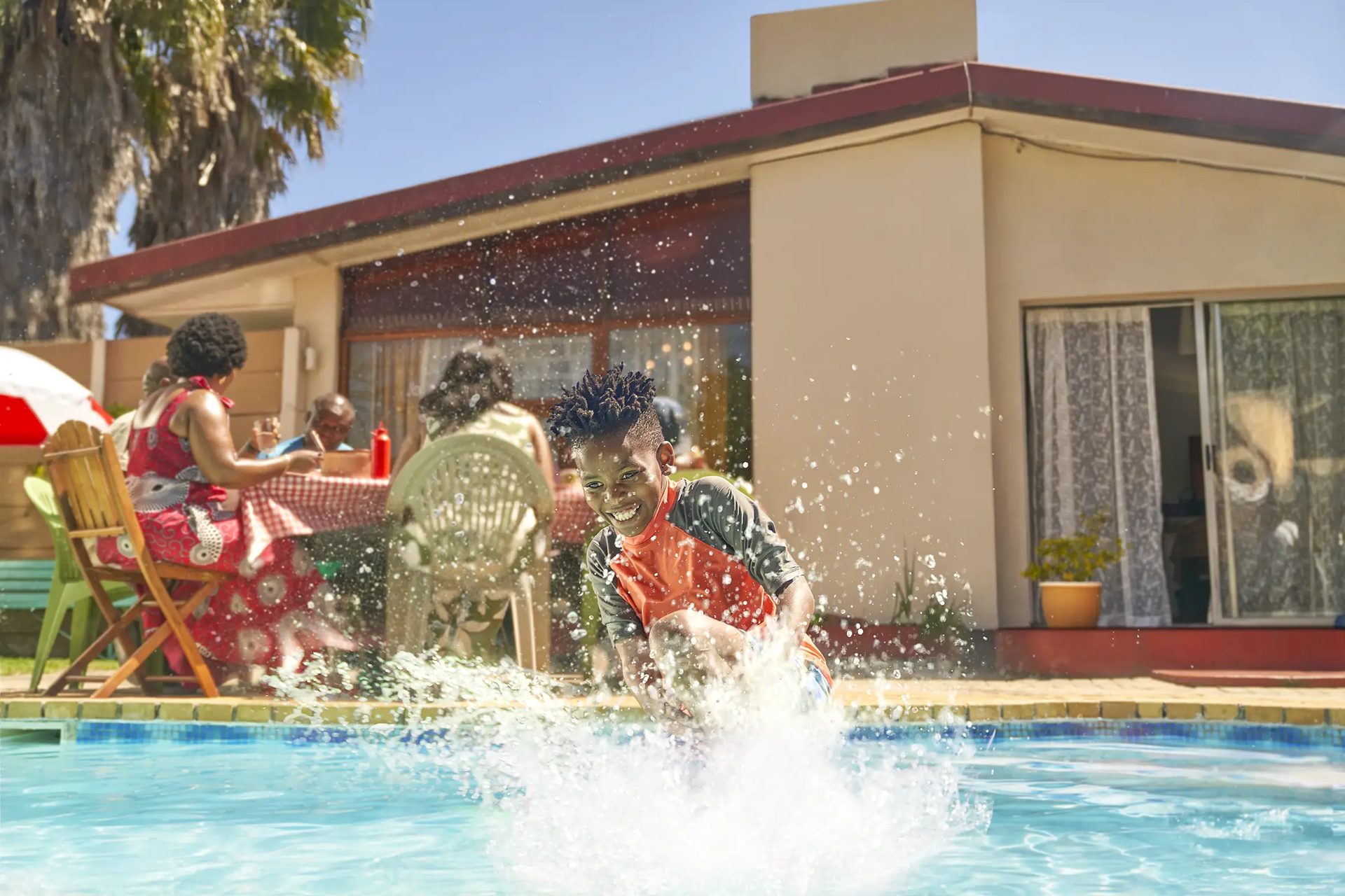 Finished artwork — sky deepened, colour graded and a full splash added as the boy bombs into the pool