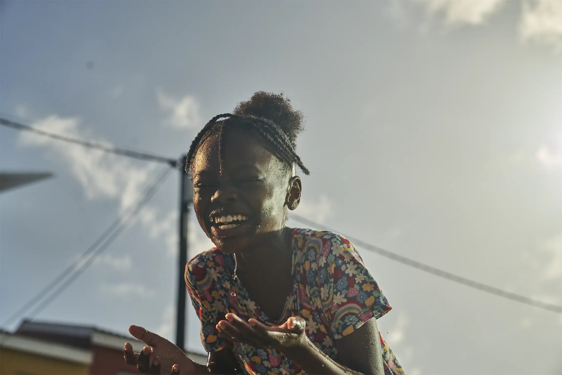 Original backlit photograph of a laughing girl against a hazy grey sky
