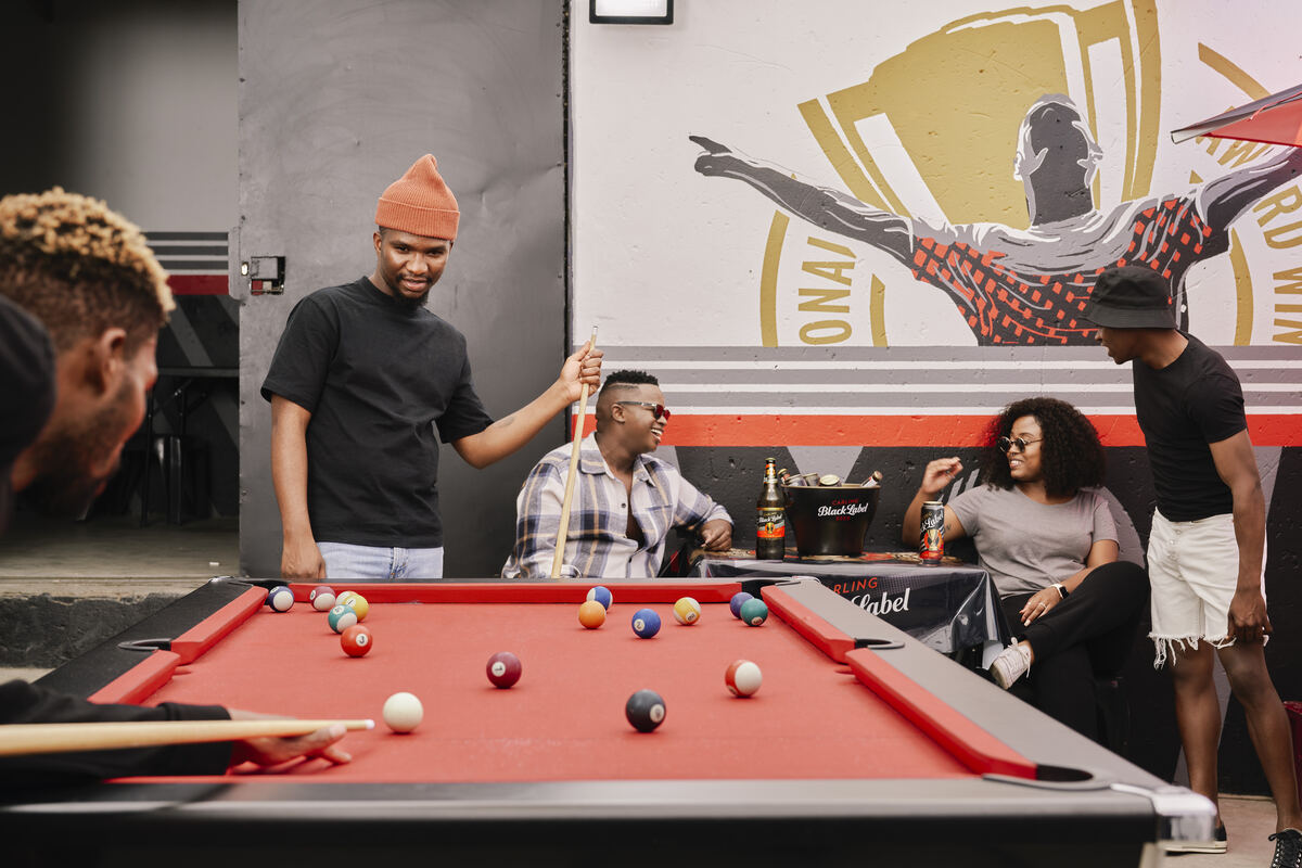 Friends around a red pool table in a local pool hall