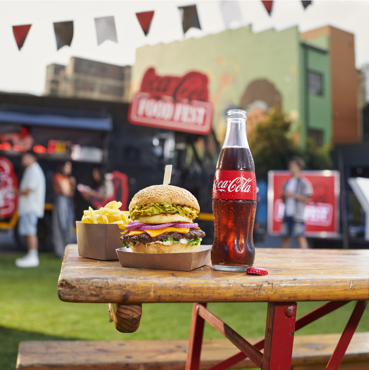 Food festival table with a loaded burger, fries and Coca-Cola