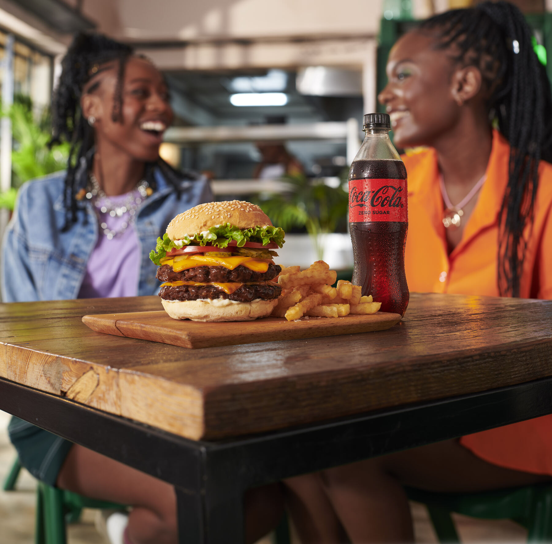 Two friends laughing over a burger and Coca-Cola at a food festival