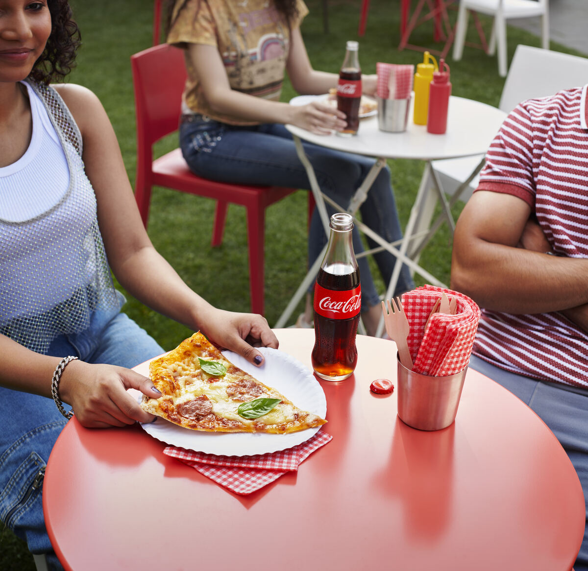 Pizza slice and Coca-Cola bottle on a red café table