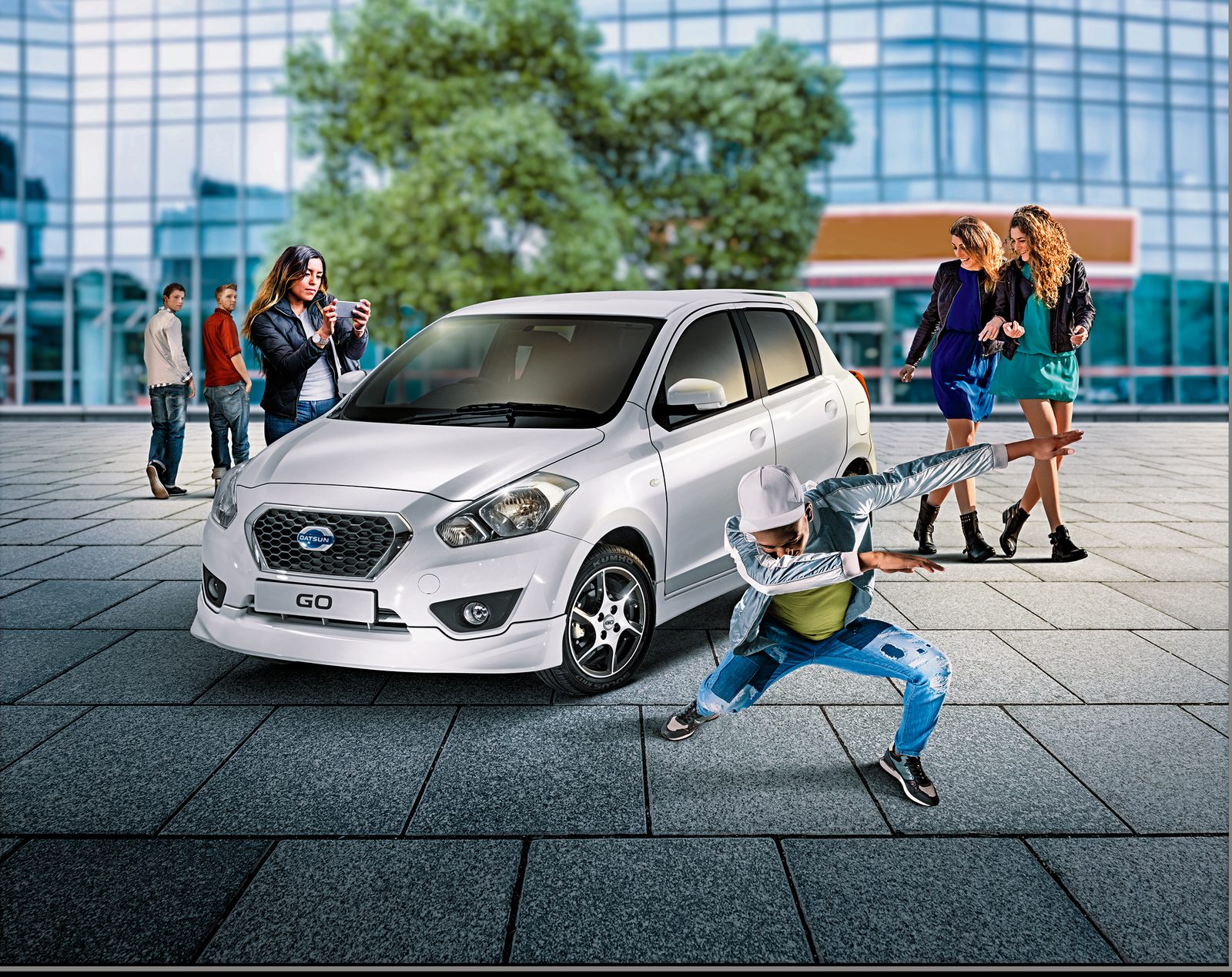 Datsun GO composite on a city square with onlookers and a street dancer