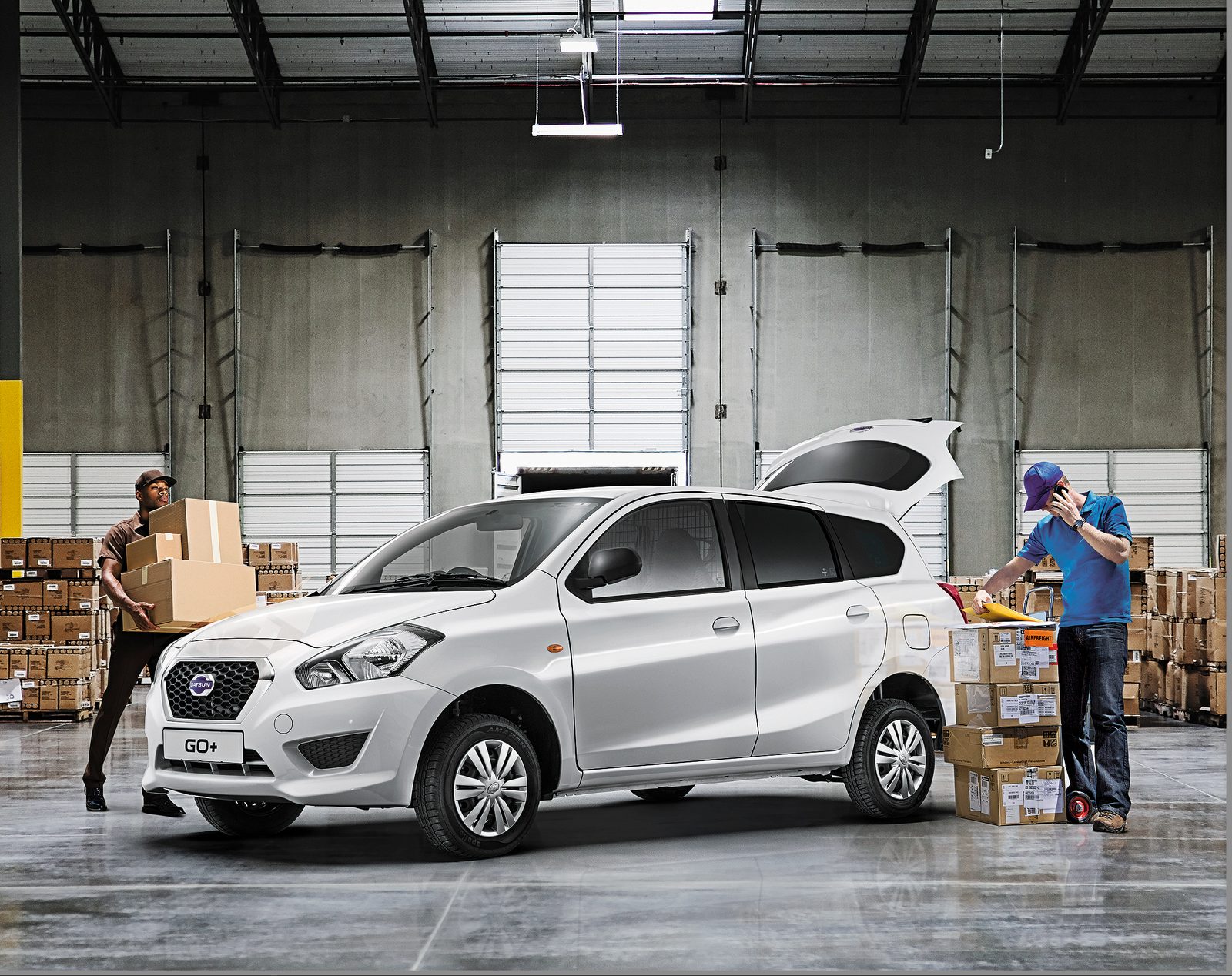 Datsun GO+ composite in a distribution warehouse, couriers loading boxes at the open tailgate