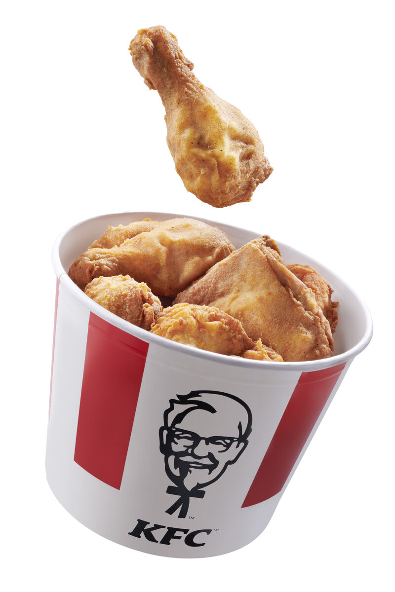 KFC bucket with a piece of fried chicken frozen mid-fall