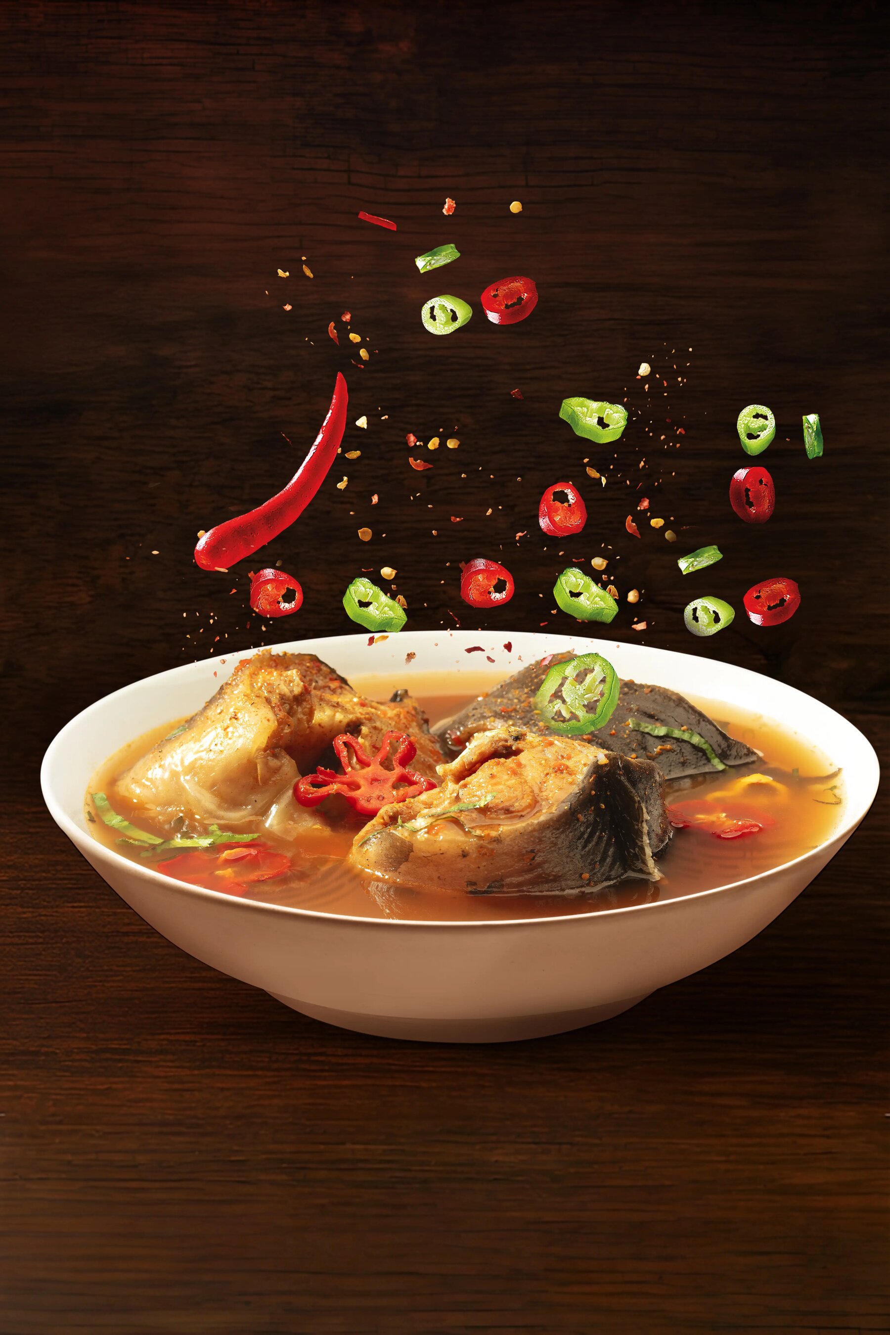 CGI composite of a spicy pepper soup with floating chillies and spices